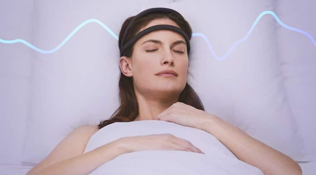 A woman laying in bed asleep with the Dreem 2 Band on her head.