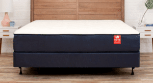 A white mattress with a red tag sitting on a wood bed frame.