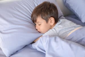 boy sleeping on a light blue pillow.