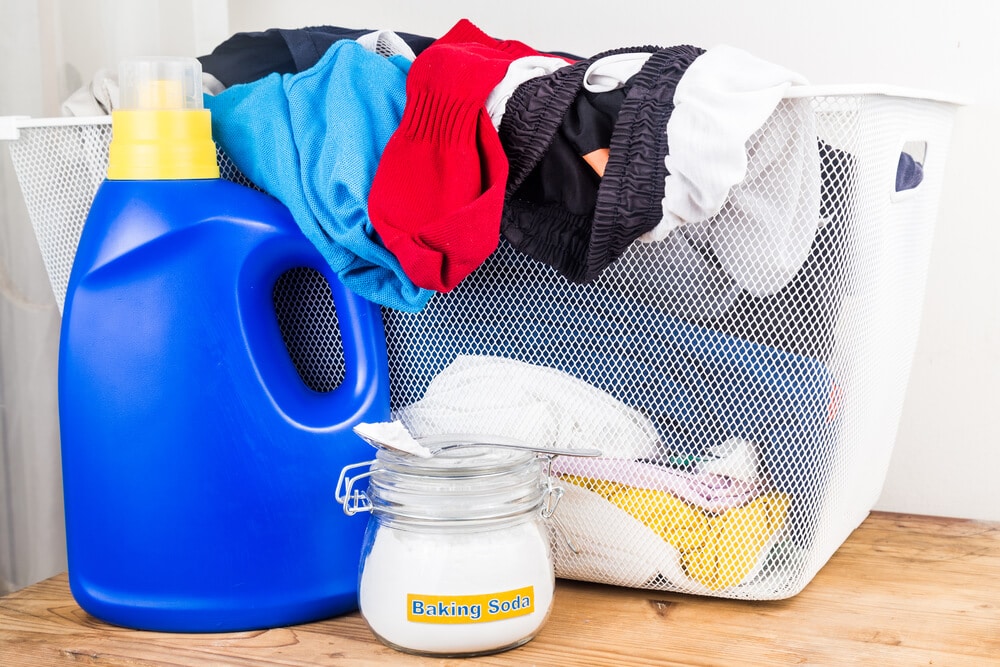 Baking soda with detergent and pile of dirty laundry