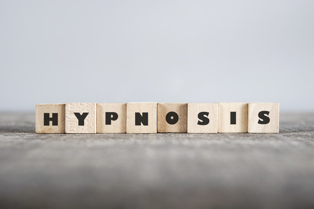 Wooden blocks spelling out hypnotherapy against a gray background.