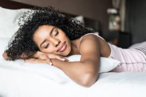 A woman sleeping in bed with curly hair.