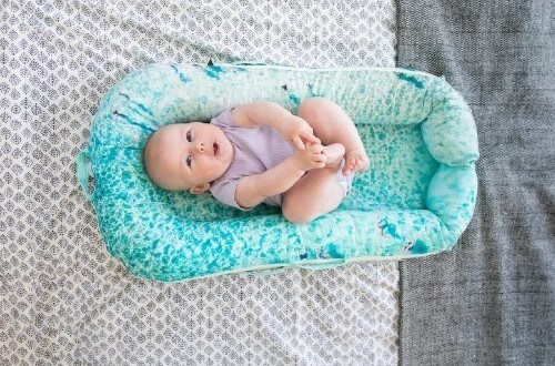 Smiling baby holds feet.