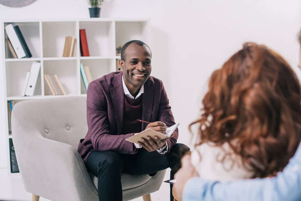 Smiling african american psychiatrist talking to young couple