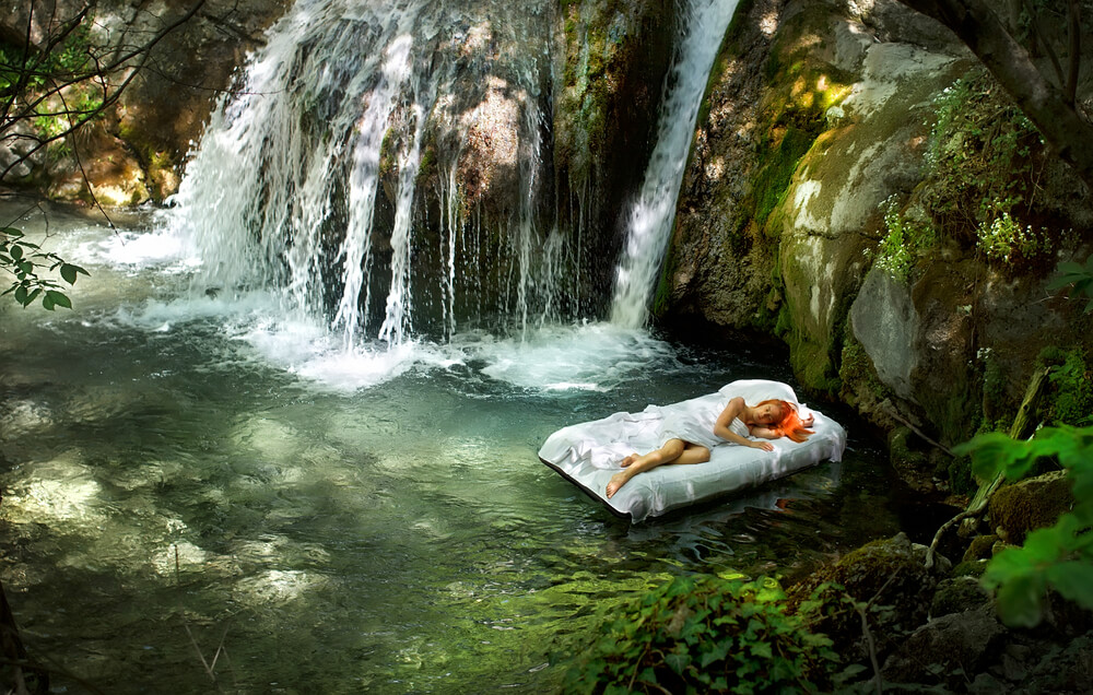 Sleeping woman in deep forest with waterfall on back; nature sounds for sleep concept.