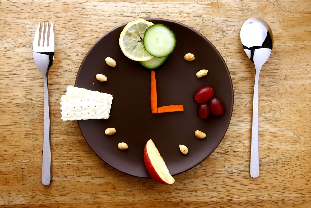 fruits, vegetables, nuts and crackers arranged on a plate like a clock