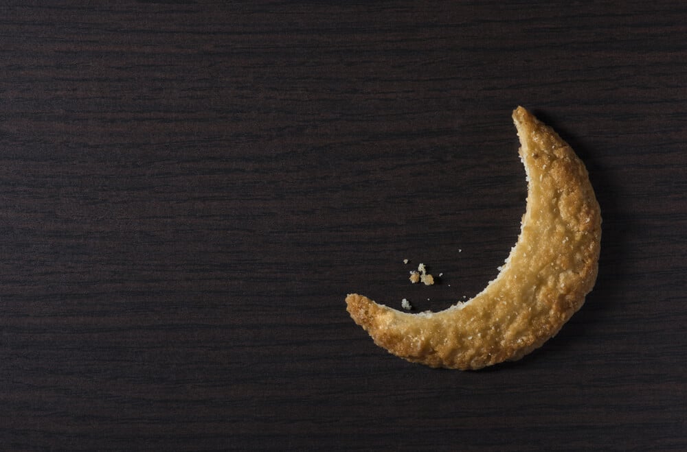 Bite of a cookie biscuit in moon shape. Moon-shaped cookie - creative idea.
