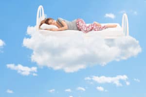 Relaxed young woman sleeping on a comfortable best foam mattress in the clouds