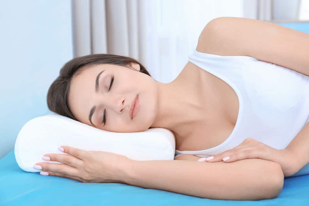 Young woman sleeping on bed with orthopedic pillow at home. Healthy posture concept