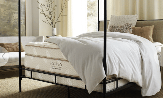 A white Saatva mattress on a black four-post bed frame.