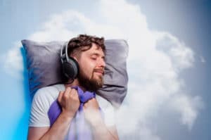 best noise cancelling headphones for sleep concept man with headphones sleeps against a cloud