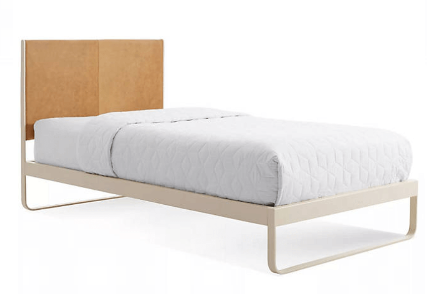 A metal and leather bed frame with white bed sheets.