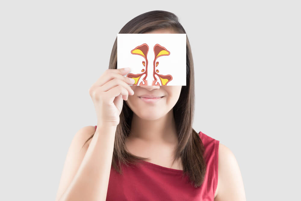 Smiling woman hold sinus picture on white paper on the gray background.