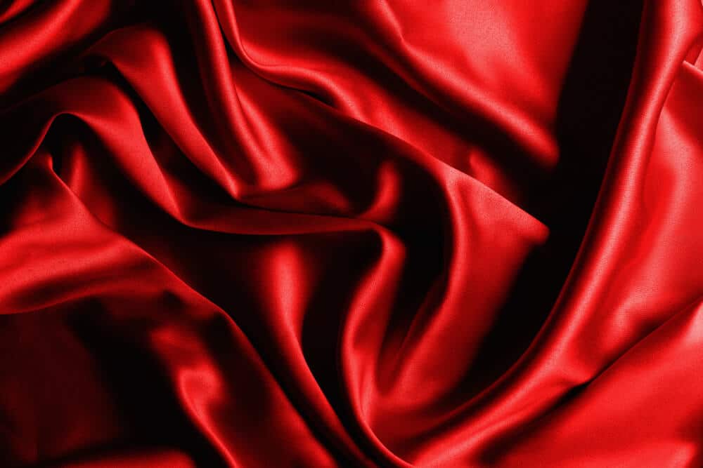 A bunched up red silky sheet; how to wash silk sheets concept art.