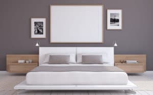 A white bed frame against a dark gray wall.