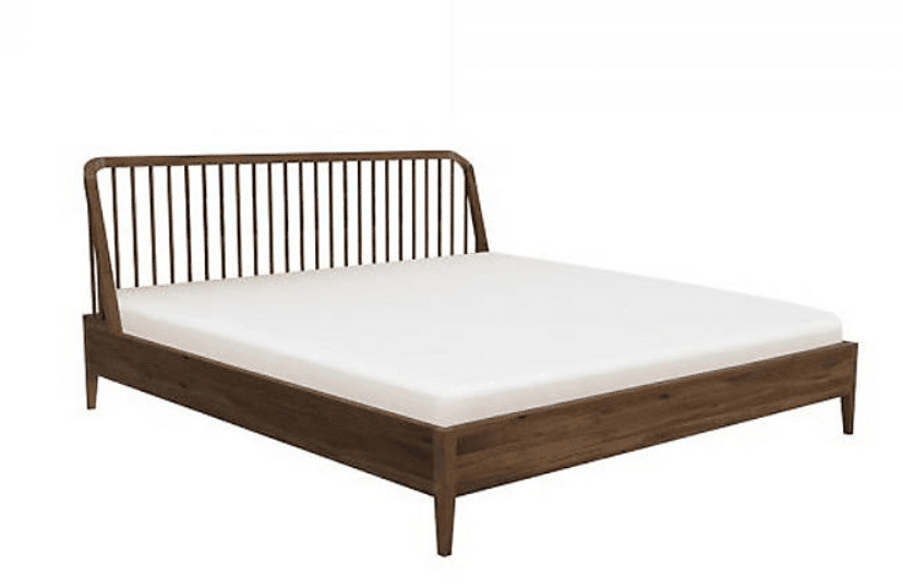 A wooden spindle bed frame with white bed sheets.