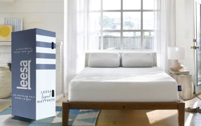 A white Leesa Legend hybrid mattress on a wooden bed frame with a blue and white box.